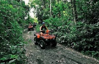 a group of people riding atvs through the jungle