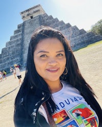 a woman posing in front of a pyramid in chichen itza, mexico