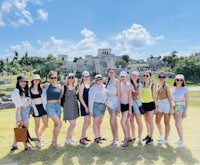 a group of women posing for a photo in front of a ruins