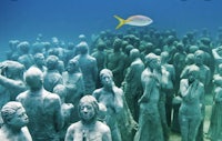 a group of statues in the ocean with a fish in the middle