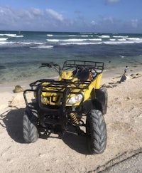 a yellow atv parked on the beach near the ocean